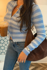 Close-up of a blue and white striped knit sweater with a partially unzipped front and cropped hem