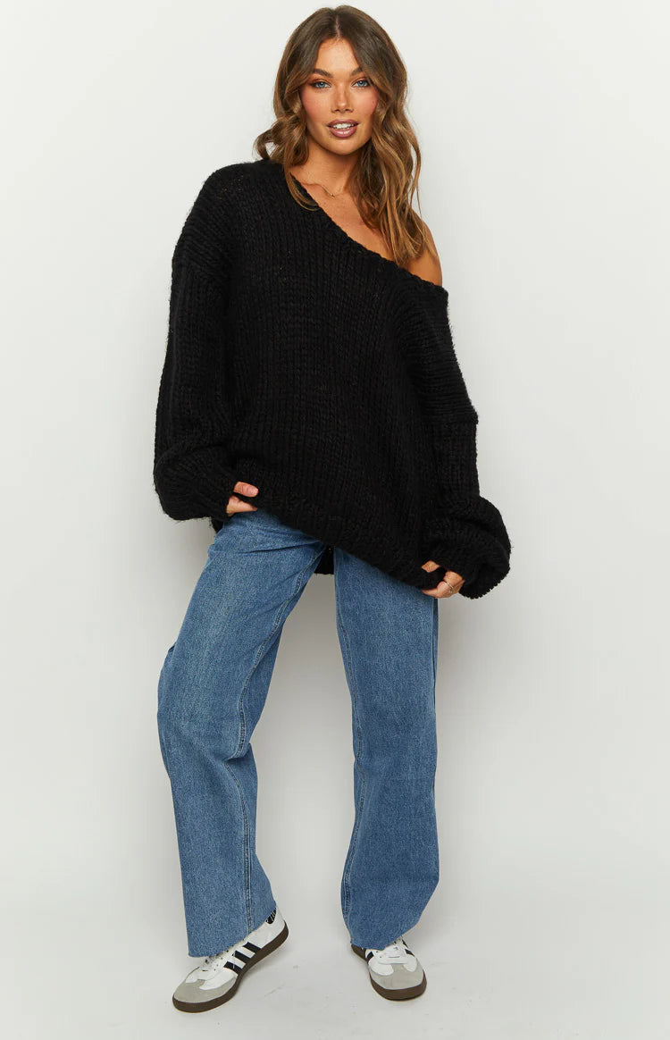 Black oversized chunky knit sweater with a wide neckline styled off one shoulder, showing the slouchy fit and distressed hem