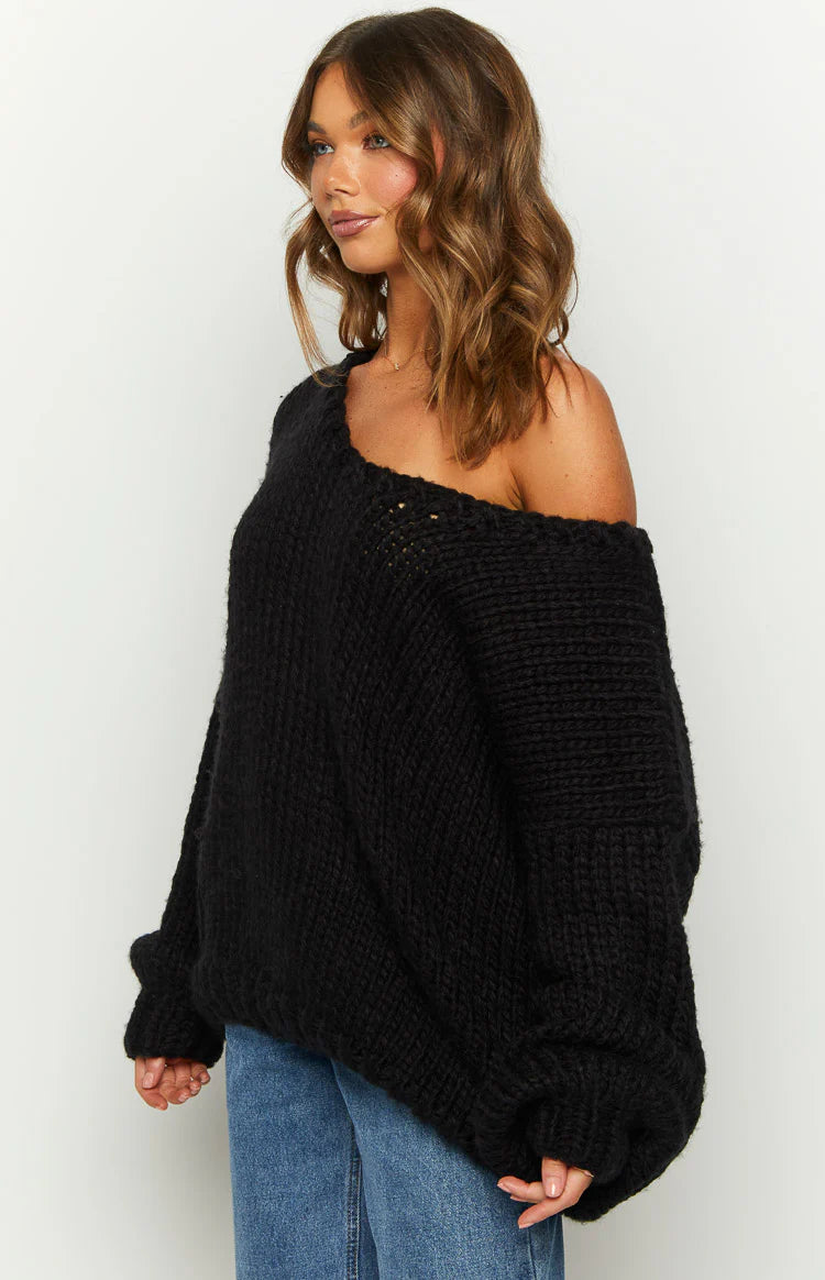 Side view of a black chunky knit sweater with an off-shoulder neckline and oversized long sleeves