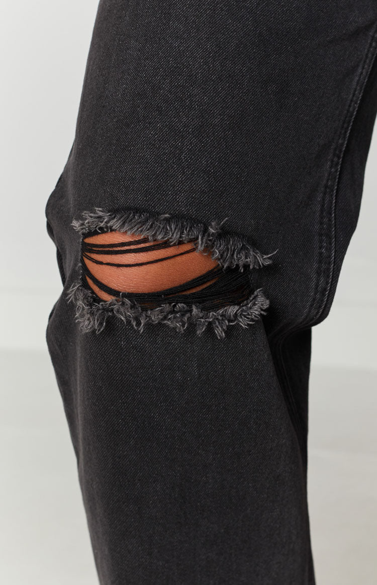 High waisted black wash wide leg jeans with distressed ripped knees and a faded denim texture