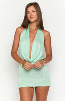 Green knit dress with necklaces on a girl in front of shops 