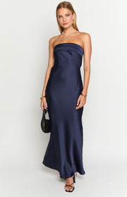 Front view of a navy strapless maxi dress with a folded bandeau neckline and flowing satin fabric