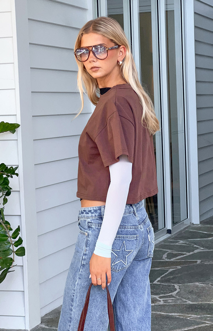 Side view of a brown relaxed fit cropped top with short sleeves layered over a white long sleeve top