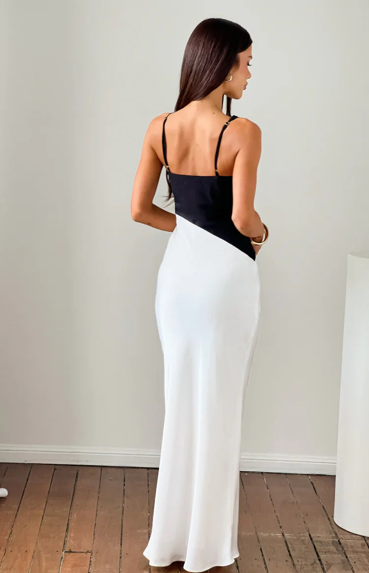 Rear view of a black and white satin maxi dress with thin adjustable spaghetti straps and a diagonal colour block design