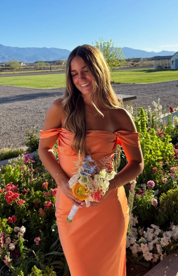 Orange off-shoulder formal dress with a draped neckline and fitted bodice in a smooth fabric
