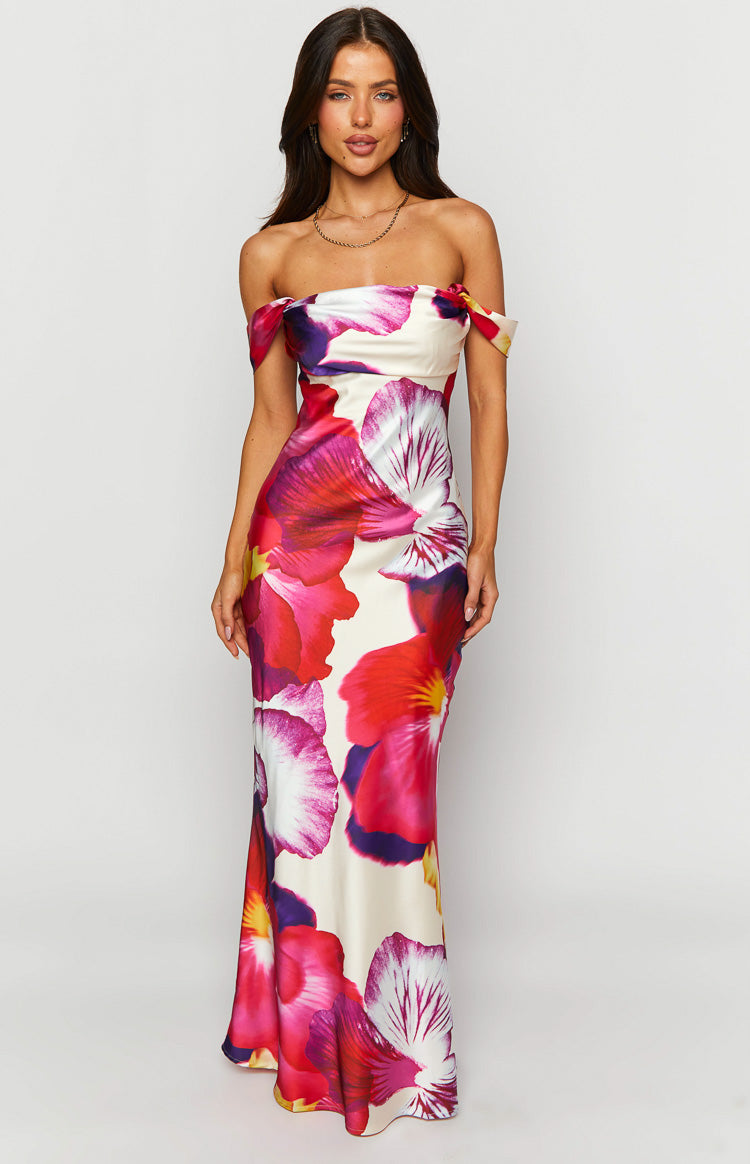 Off-shoulder neckline of a cream formal dress with large pink, red, and purple floral print, fitted bodice and flowing maxi skirt