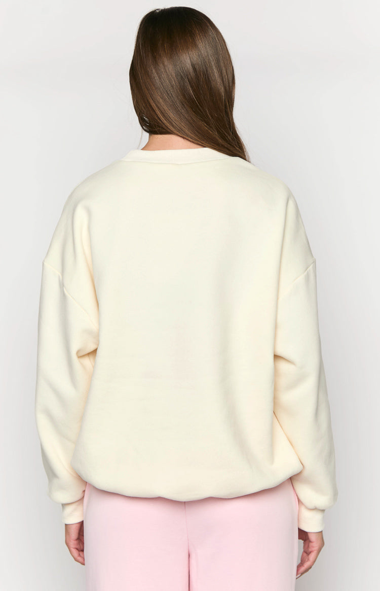 Rear view of the cream crew neck sweater with a relaxed fit, dropped shoulders, and ribbed hem