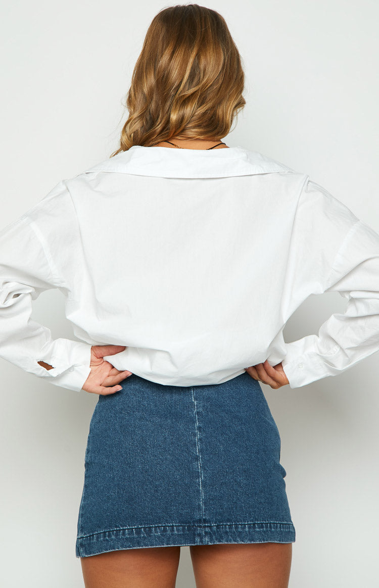 Close-up of the silver buckle, eyelets, and frayed distressed detailing on the blue denim mini skirt