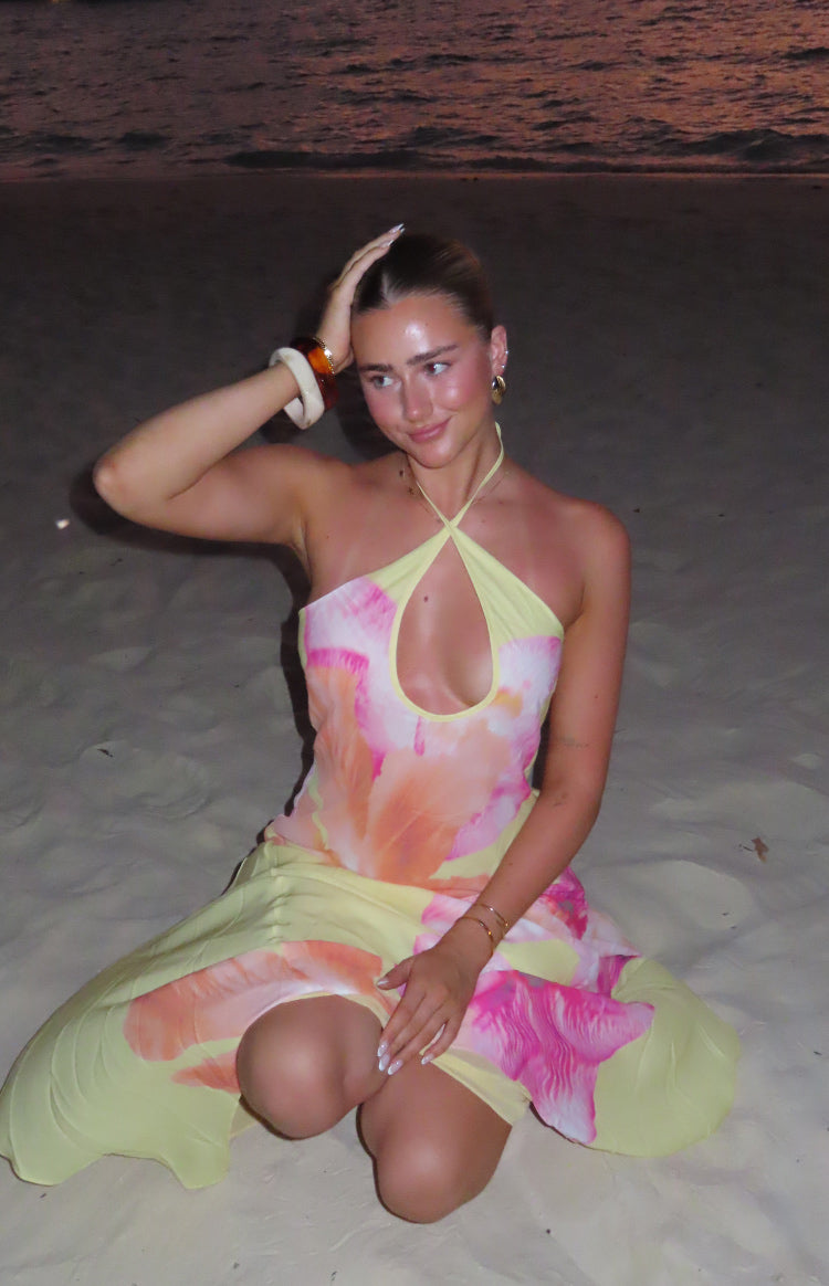 Front view of a yellow pink and orange floral halter maxi dress with a keyhole cutout and a flowy skirt