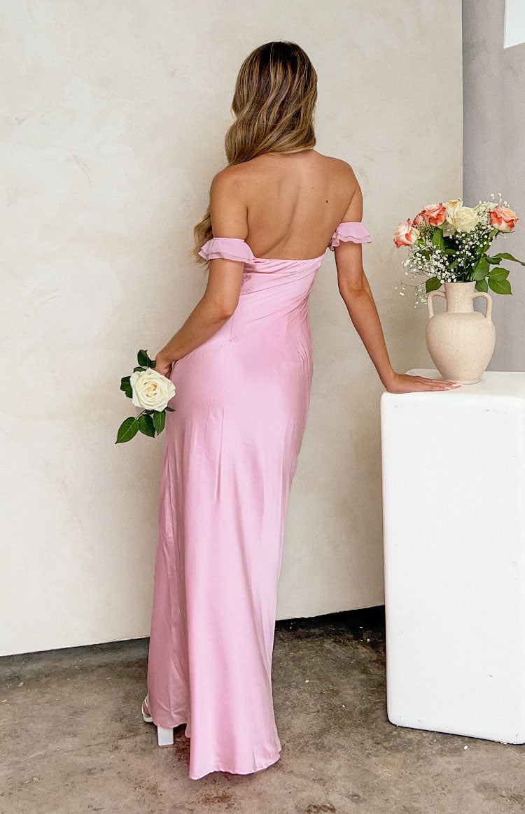 Close-up of the draped strapless neckline and ruffled off-shoulder strap of a pink satin maxi dress