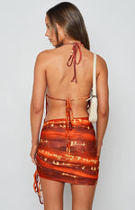 Rear view of the red and orange patterned mini dress with a halter neck tie, open back, and ruched skirt