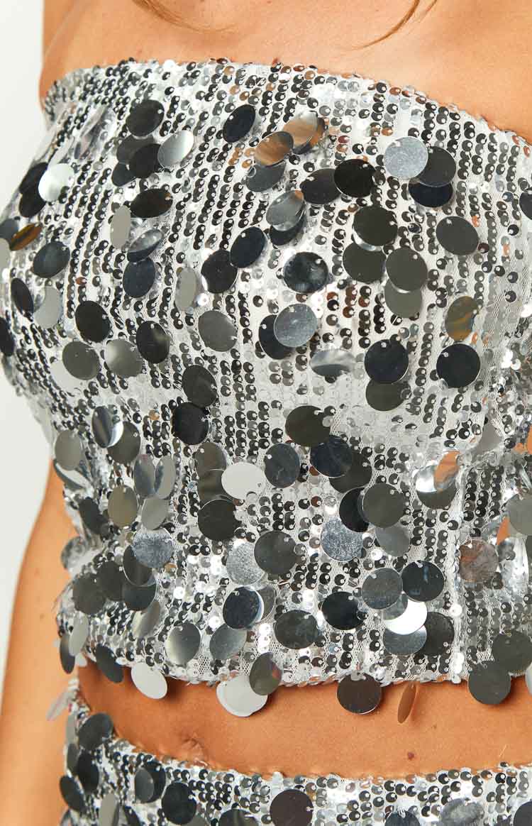 Close-up of the silver sequin crop top showing the strapless neckline and irregular hemline