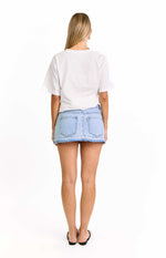 Rear view of a light wash denim mini skirt with two back pockets and a distressed raw hem