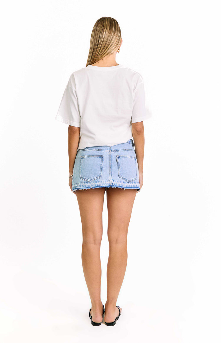 Rear view of a light wash denim mini skirt with two back pockets and a distressed raw hem