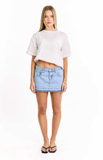 Front view of a light wash denim mini skirt with a distressed raw hem and classic five-pocket design