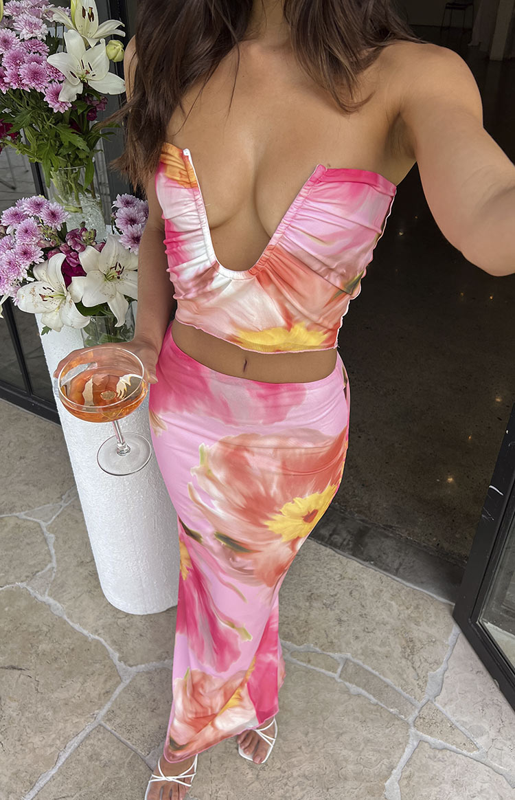 Deep plunge V-neckline of a pink floral strapless crop top with ruched detailing