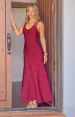 Full length view of a burgundy bandage maxi dress with a V-neck, thin straps, and a flared hem