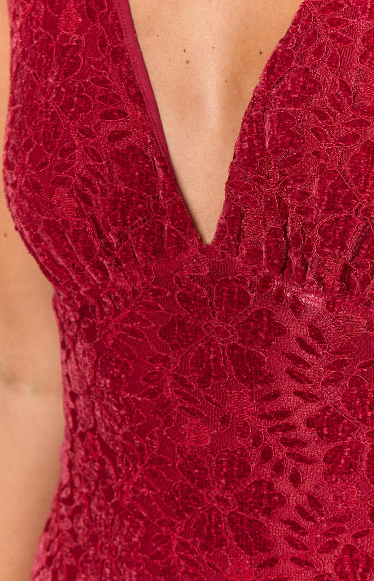 Detail shot of the deep V-neckline and textured red floral lace on the bodice of the maxi dress