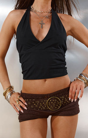 Close up of a brown studded belt with a large circle buckle styled with shorts and a halter top a great Festival accessory