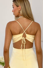 Rear view of a yellow satin mini dress with criss-cross spaghetti straps, ruched back, and tie closure
