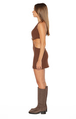 Side view of a brown fitted mini dress with a halter neckline, side cutouts, and gold chain detail