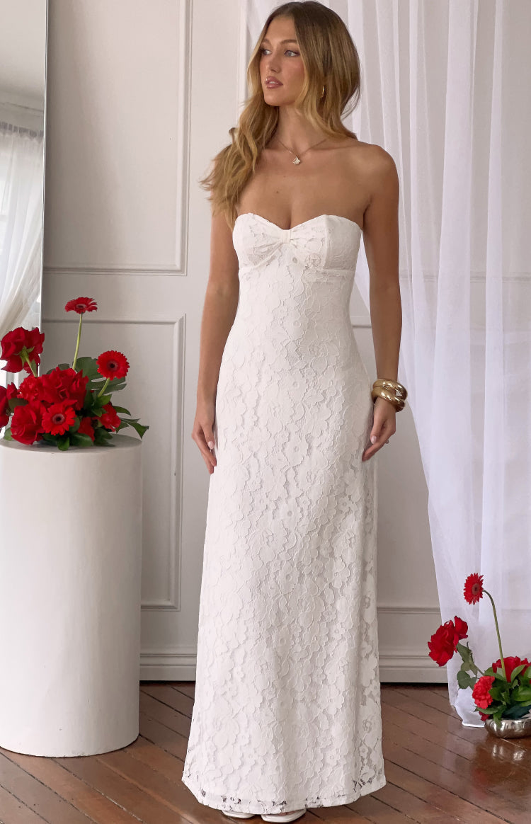Full length front view of a white lace strapless maxi dress with a fitted bodice and a small bow detail on the bust