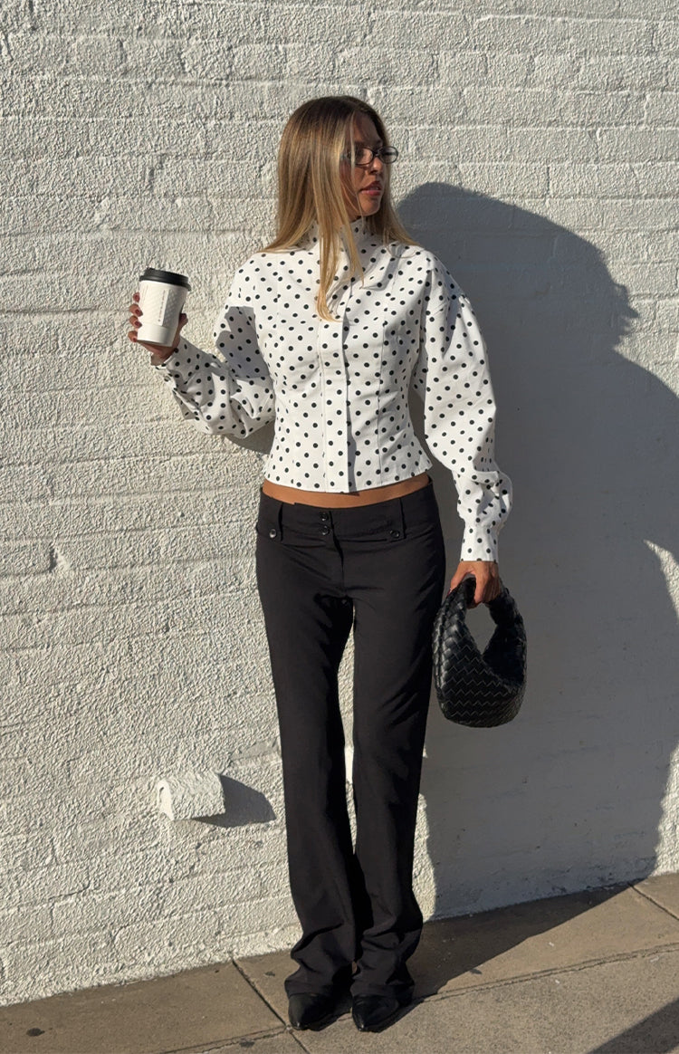 Front view of a white polka dot jacket with a high neck, fitted bodice, and puff long sleeves