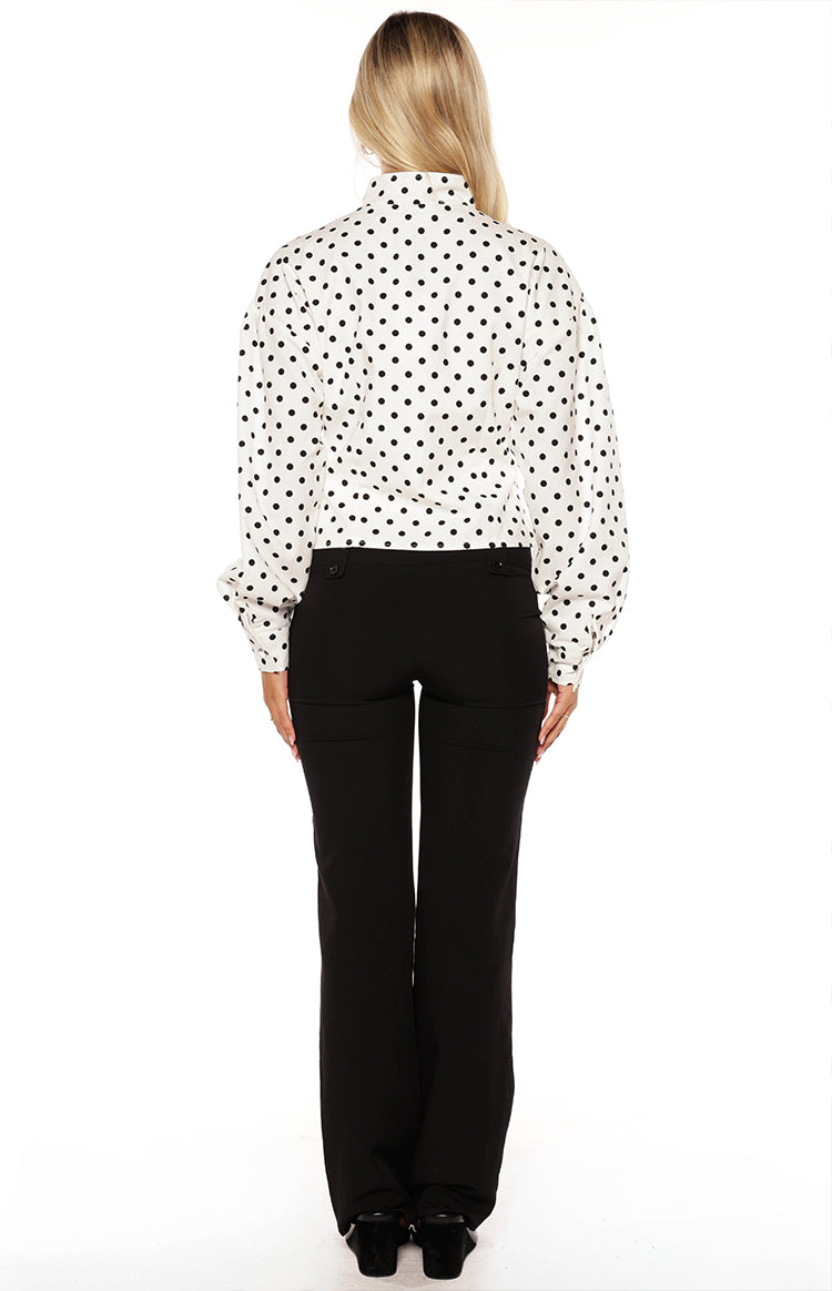 Back view of a white jacket with black polka dots, voluminous long sleeves, and a stand collar