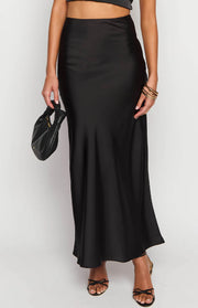 Close-up of the black satin maxi skirt showing its smooth texture and flowy drape