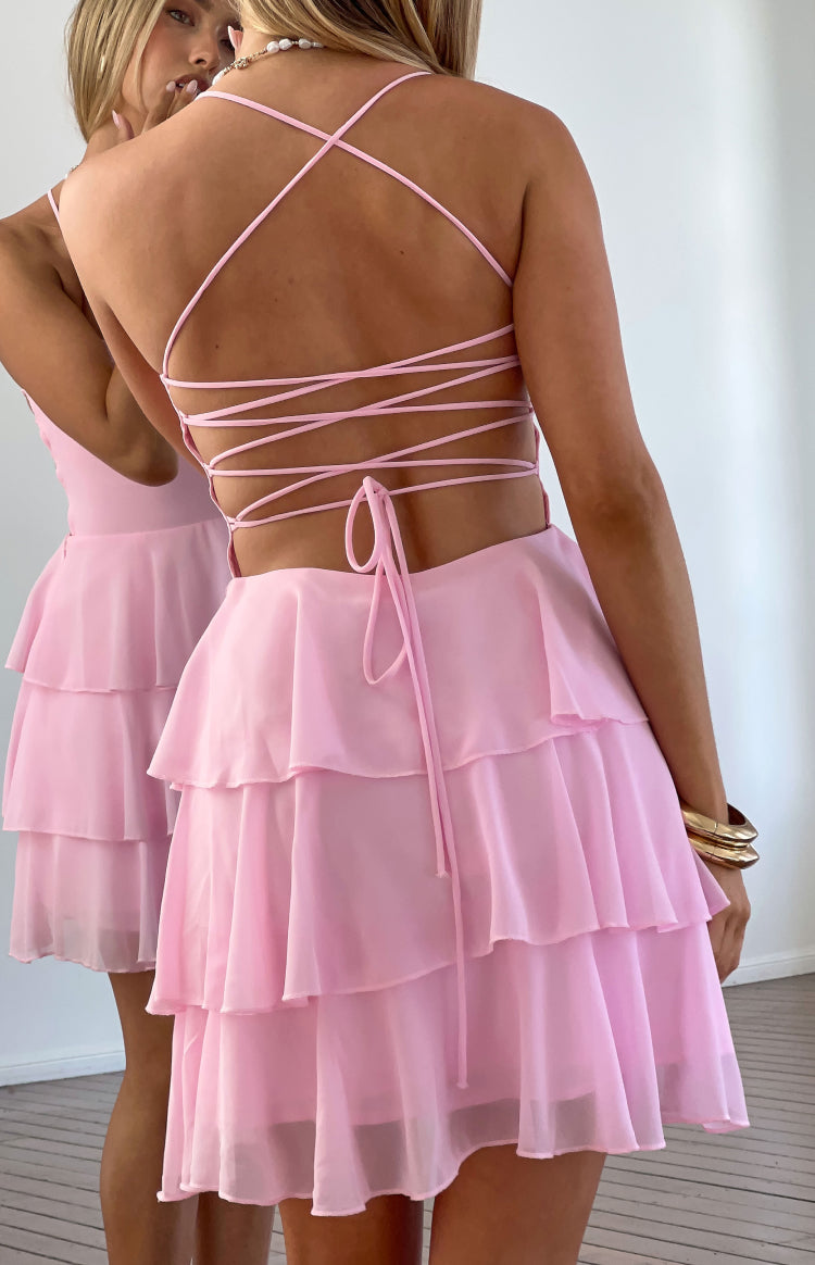 Rear view of a pink mini dress showing the criss-cross tie-back straps and tiered ruffle skirt