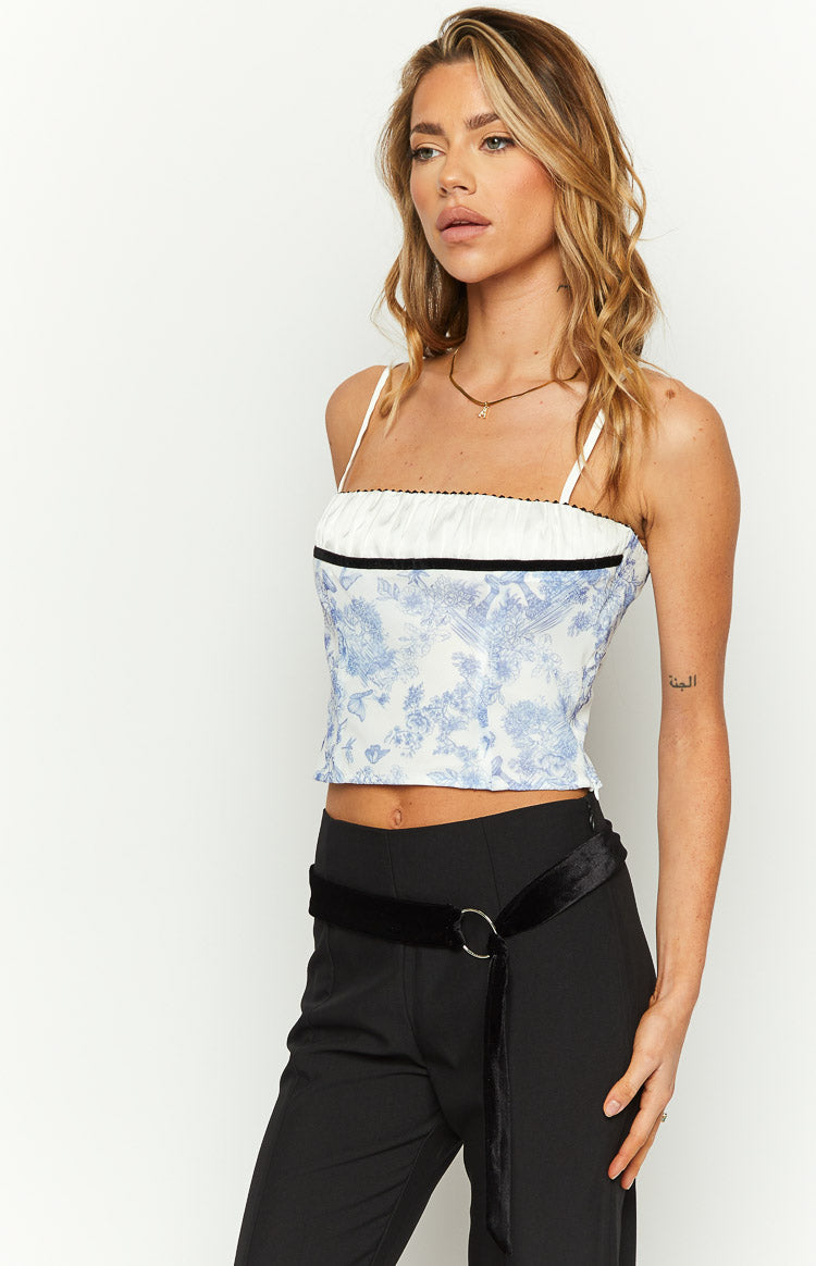 Blue toile print crop top featuring a white ruched bust, black velvet trim, and thin spaghetti straps