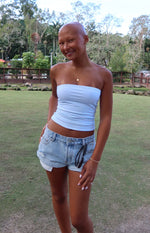 Light wash denim shorts with distressed rips, frayed hems, and a relaxed fit