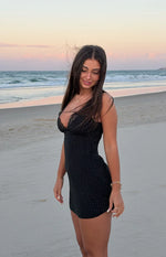 Side view of a black polka dot mini dress with a fitted silhouette and lace trim V-neck