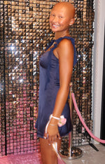 Side view of a navy satin mini dress with ruffled shoulder straps and a draped bust
