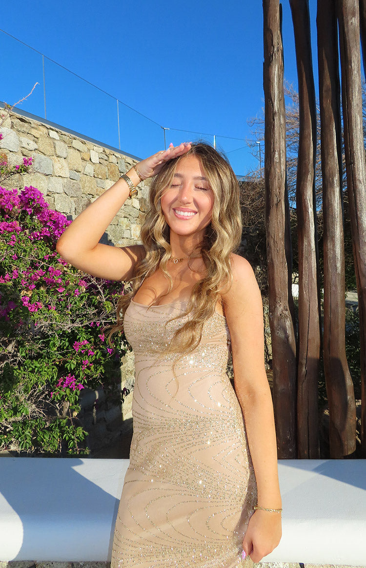 Upper body view of a gold slip formal dress with a strapless neckline and intricate sequin swirl pattern