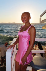 Side view of a hot pink satin mini dress with a sweetheart neckline and floral embellished spaghetti straps