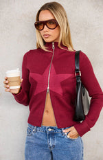 Partially unzipped burgundy knit sweater showing a large darker star pattern and ribbed hem