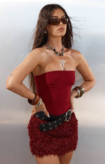 Front view of a burgundy strapless mini dress with a smooth fitted bodice and a shaggy fur textured skirt