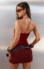 Side view of a burgundy strapless mini dress with a smooth bodice and shaggy fur skirt