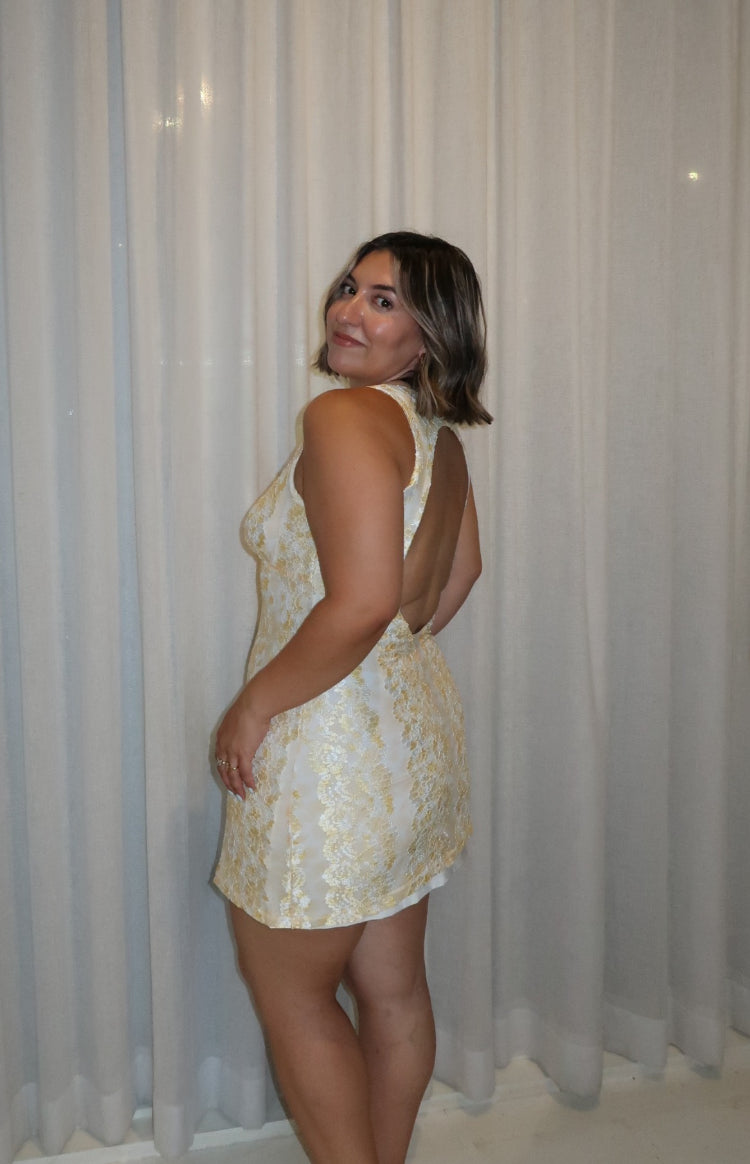 Side view of the yellow lace mini dress, highlighting its high neckline and deep open back