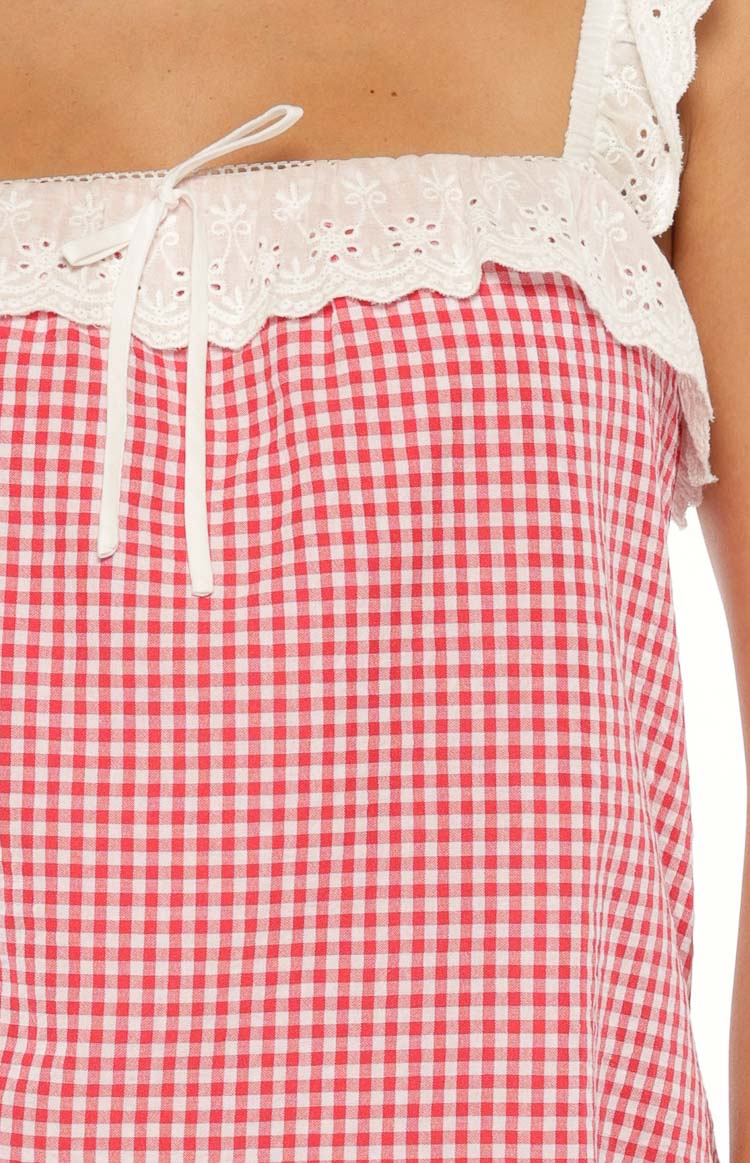 Close-up of the red gingham mini dress with white eyelet lace trim, front tie, and ruffled lace strap