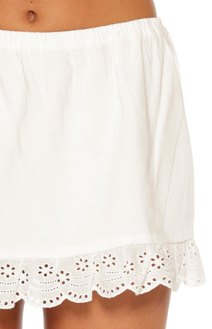 Close-up of the white mini skirt's elasticated waistband and scalloped broderie trim with floral cutouts