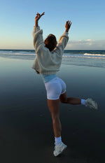 Rear view of a cream chunky knit cardigan with an oversized fit and cropped hem