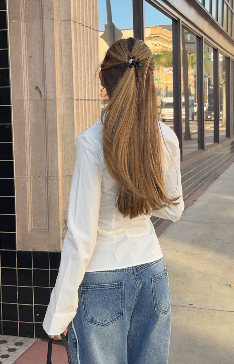 Rear view of the white fitted long sleeve shirt, showing the tailored back seams and long cuffed sleeves