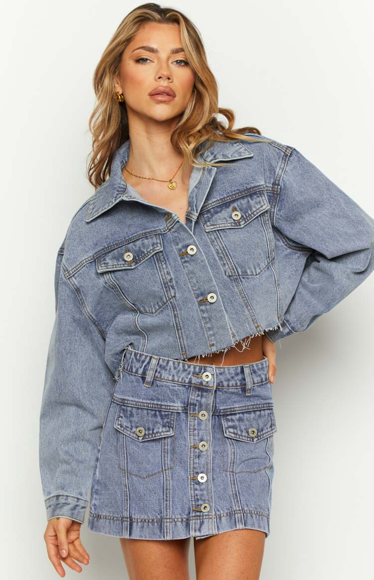 Front view of a mid wash denim mini skirt with a full button-front and two flap cargo pockets