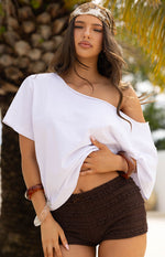 Close-up of chocolate micro shorts with a textured, ruffled surface and a small bow detail at the front