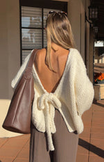 Close-up of a cream chunky knit cardigan with a tie-up front closure and wide ribbed cuffs