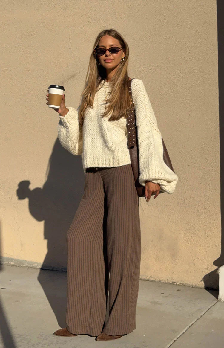 Side view of a cream chunky knit cardigan with a prominent side tie closure and relaxed long sleeves