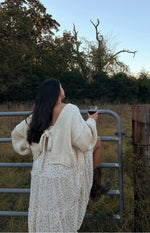 Rear view of a cream chunky knit cardigan with a deep V-back and a tie-up closure at the lower back