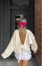 Rear view of a cream chunky knit cardigan with voluminous sleeves and a cropped hem